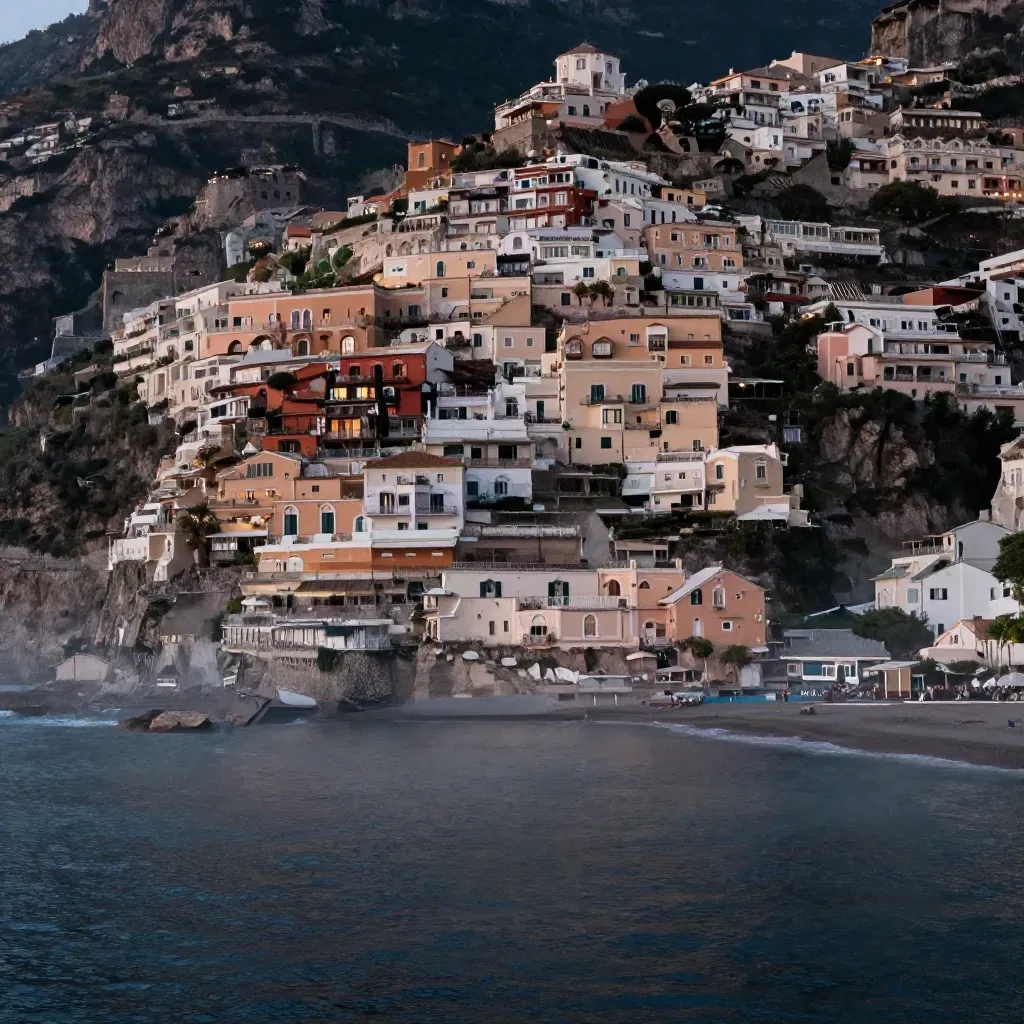 Scogliera di Positano al crepuscolo, case illuminate e mare scuro in una vista alta e calma